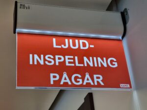 En röd skylt med vit text: Ljudinspelning pågår.